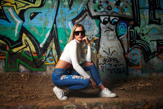 blonde sexy woman with sunglasses on wall with graffiti