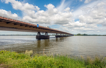Fototapeta na wymiar Moerdijk road bridge over the Hollandsch Diep river seen from the southern bank in the province of Noord-Brabant. The photo was taken on a sunny day in the summer season.