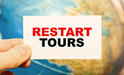 A traveler waiting for RESTART TOURS with a card during self-isolation.