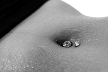 Belly button or navel piercing, of young woman wearing jeans isolated on white. Close-up macro...