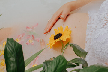 Pregnant girl in a bath with milk and flowers