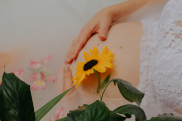 Pregnant girl in a bath with milk and flowers
