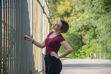 Obraz premium A girl stands on the street holding a metal fence