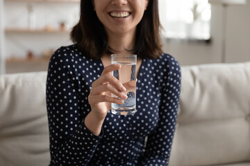 Close up smiling young vietnamese ethnicity asian woman holding glass of fresh pure water, taking...