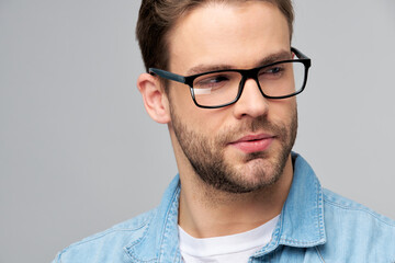 Close-up Portrait of young handsome caucasian man in jeans shirt over light background