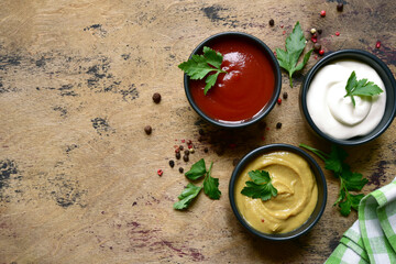 Set of popular sauces in a black bowls . Top view with copy space.