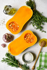 Halves of raw organic butternut squash with spices and ingredients for making . Top view with copy space.