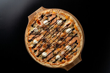 Smoked salmon pizza with small mozzarella balls, top view on black background