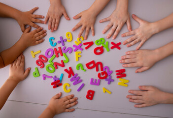 Obraz na płótnie Canvas Plastic alphabet letters with kids hands, top view