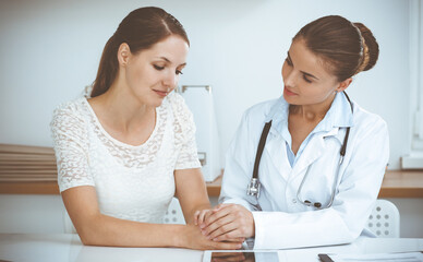 Woman-doctor reassuring her female patient while sitting at the desk. Medicine concept