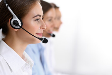 Call center. Group of operators at work. Focus on beautiful business woman in headset