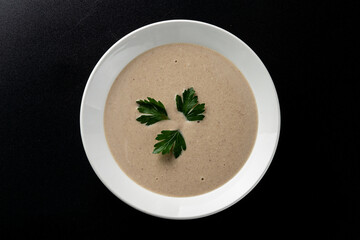 Minimalist and stylish photo for a restaurant menu: creamy mushroom soup with herbs