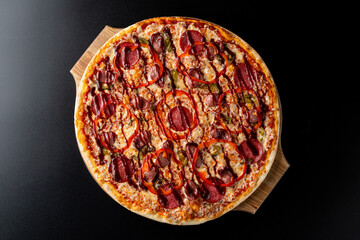 Top view of a whole pepperoni pizza on black background