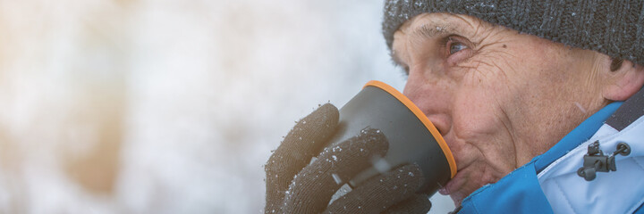 Mature man in knitted cap takes sip of hot tea from hikes cup