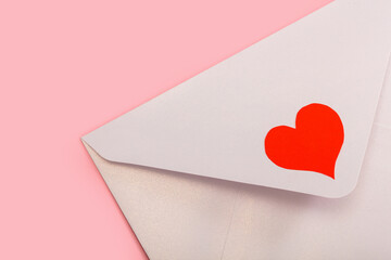 light mother-of-pearl paper envelope with red heart isolated on pink background