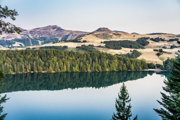 View of Lac Pavin in Auvergne (France), early in the morning. The Puy de Sancy volcano can be seen in the background