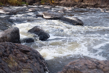mountain river rapids with fast water and large rocky boulders in the water and the massive rocks