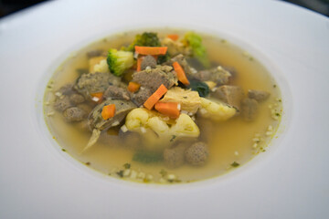 Ein weißer Teller Gemüsesuppe, Hühnersuppe mit Karotten, Leberknödel und Bio Gemüse, Speisekarte