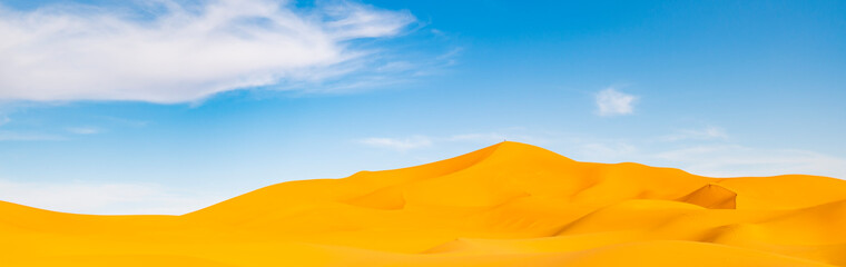 Fototapeta na wymiar (Selective focus) Stunning view of some sand dunes illuminated during a sunny day in Merzouga, Morocco. Natural background with copy space.