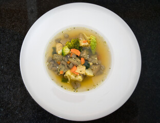 Ein weißer Teller Gemüsesuppe, Hühnersuppe mit Karotten, Leberknödel und Bio Gemüse, Produktbild