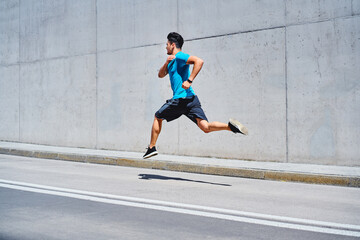 Fototapeta premium Athletic man sprinting running on city street
