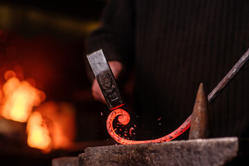 Blacksmithing. The blacksmith on the anvil measures the width of the split product and glowing...