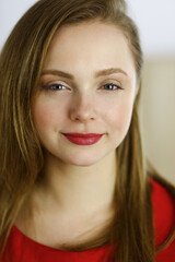 Naklejka premium Head shot of a smart confident smiling millennial european woman standing with folded arms at home. Attractive young teenager student girl freelancer looking at camera, dressed in red