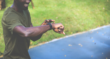 Sport African American man checking performance or heart rate pulse trace. Sport and fitness outdoors. Black Male runner looking sports smart watch
