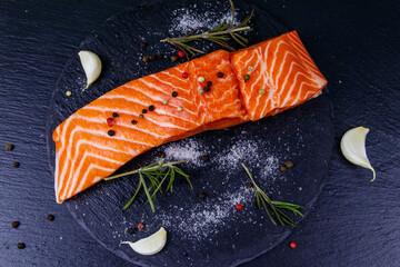 Raw salmon fillet with spices on black slate. Top view