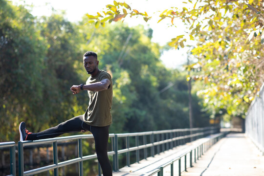 Sport African American man checking performance or heart rate pulse trace. Sport and fitness outdoors. Black Male runner looking sports smart watch