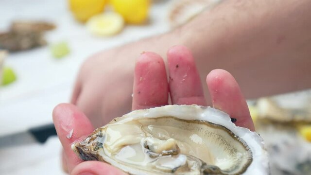 Close-up Chef preparing fresh Oysters from crushed ice by opening with a knife. Concept of eating raw seafood seashell oysters by cracking the shell.