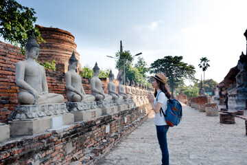 Asian woman tourists carrying a backpack and wearing a hat Visit Wat Yai Chaimongkol, the historical archaeological site of Phra Nakhon, Ayutthaya.