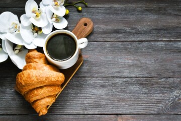 coffee and croissant.Valentine Day Morning background. Breakfast with Cup of Coffee, fresh Croissants and orchid flower on wooden background. Flat lay, copy space.