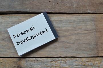 Obraz premium Top view of notebook written with text PERSONAL DEVELOPMENT over wooden background. 