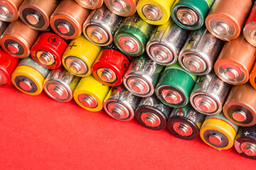 Stack of used batteries on a red background. AA batteries