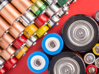 Many different alkaline batteries on a red background. Recycling disposable batteries
