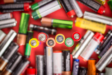 Background of batteries of different size and manufacturers on a red background. Recycling...