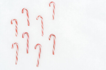 Christmas candy canes on a white snow background. There is a place for text .Concept, winter background, congratulations on the new year Christmas.