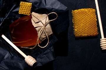 Honey background. Natural honey comb and a wooden spoon . On black rustic table.