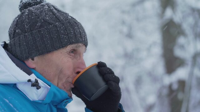Old tourist drinking hot tea from thermos mug close view. Concept healthy lifestyle.