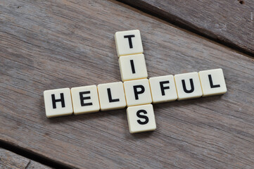 Top view of alphabet letters with text HELPFUL TIPS over wooden background. 