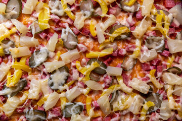 Top view hot ananas pizza with cheese and bell pepper decorated with salami, gherkins