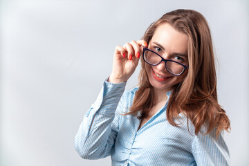 beautiful girl in a blue shirt takes off glasses on a white background. isolated