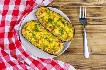 Baked stuffed eggplants on a wooden table. Top view. Healthy food and dieting concept