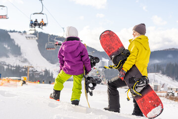 mother and daughter with snowboards at winter resort