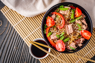 delicious glass noodles with tuna and vegetables on a dark wooden rustic background
