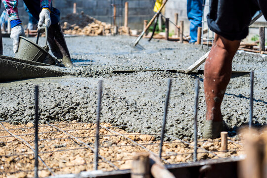 image of Construction workers are pouring a building foundation or house. Concrete works with the mixer truck and people with shovels. Labour builders at the construction site. pouring concrete slab