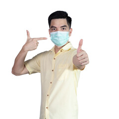 COVID-19 Coronavirus portrait handsome young asian man wearing yellow shirt and mask protection from covid 19 and thumbs up sign isolated on white background in studio. Asian people. COVID-19 concept.