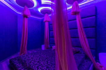 Fototapeta na wymiar Romantic lounge, violet light color. Oriental style and a baldachin.