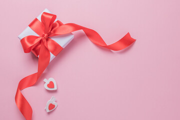 Gift box with a red ribbon on a pink background. Place for text. Happy Valentine's Day.